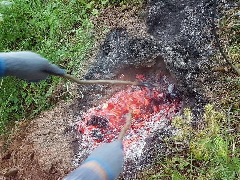 Разгребаем пышущие жаром угли в земляной печи для запекания курицы в фольге