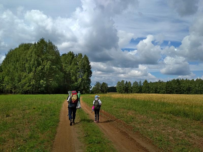 Полевая дорога, туристы и облака на небе